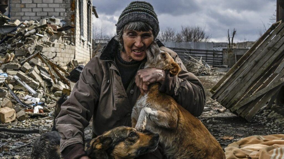 KHARKIV REGION, UKRAINE - MARCH 12: A woman pets the dogs among the debris in Kamianka village near Izium as civilians return to the village, which had been evacuated due to destructions and security reasons and try to make lives under harsh conditions amid Russia-Ukraine war, in Kharkiv region, Ukraine on March 12, 2023. (Photo by Muhammed Enes Yildirim/Anadolu Agency via Getty Images)